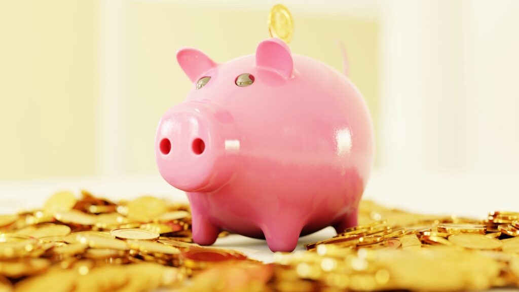 Pink piggy bank surrounded by gold coins representing emergency fund savings